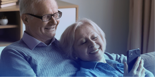 An older couple sitting together at home, looking at a smartphone